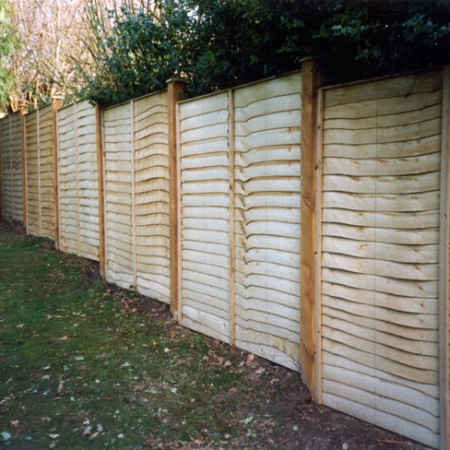 Waney Edge fence panels installed stepping down a slope on 100x100mm posts with post caps.