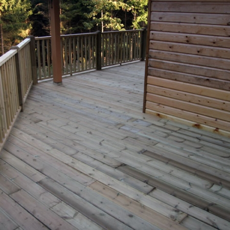 A full deck around a building installed by Tate Fencing for a customer, using grooved and reeded deck boards